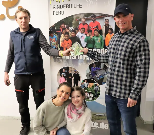 Spendenübergabe vor dem Plakat der Kinderhilfe Peru