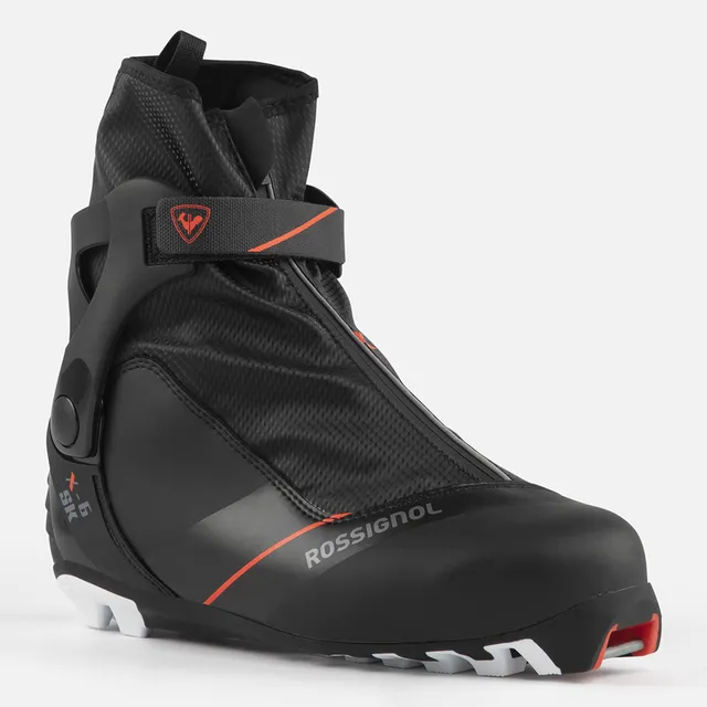Der ROSSIGNOL X-6 SKATE ist ein schwarz-roter Langlaufschuh mit hoher Manschette, Reißverschluss, Klettverschluss, stabiler weißer Sohle, strukturiertem Material und auffälligem Rossignol-Branding - erhältlich bei Mr. Bike Lichtenfels.